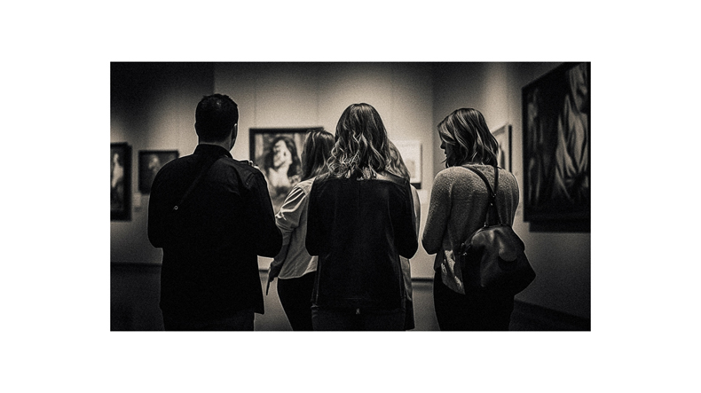 A group of people looking at paintings in an art gallery.