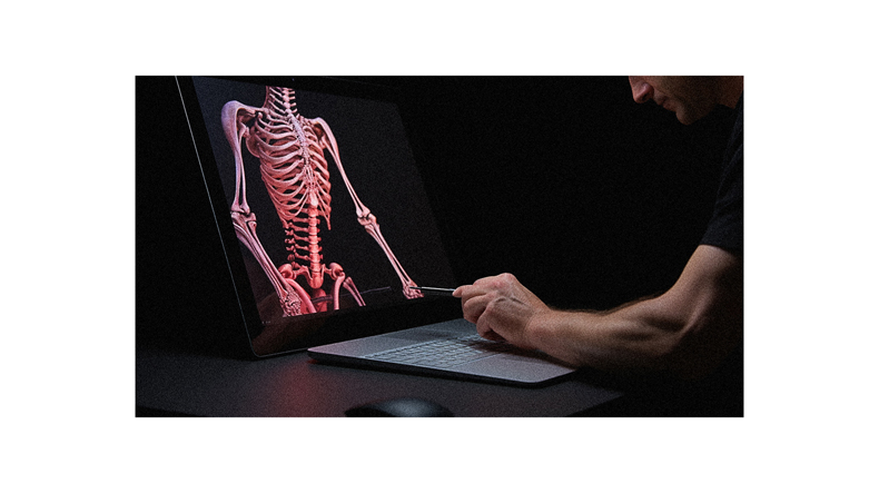 A man working on a laptop with a skeleton on the screen.