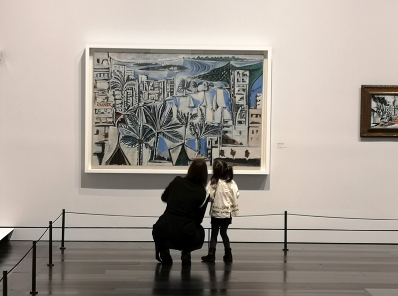 A woman and a child looking at a painting in a museum.