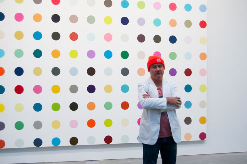 A man standing in front of a colorful polka dot painting.
