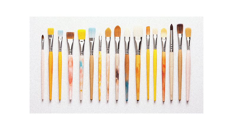 A group of brushes are lined up on a white surface.