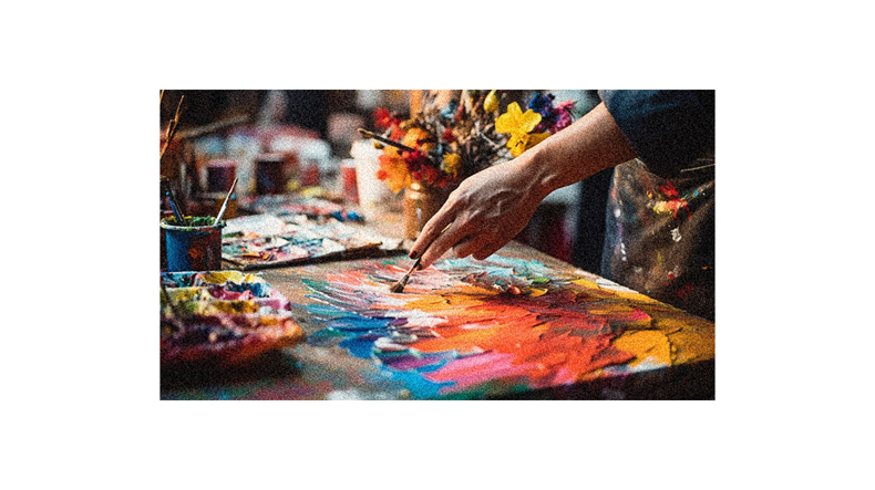A person is painting on a table with colorful paints.