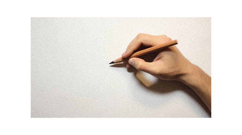 A hand holding a pencil on a white surface.