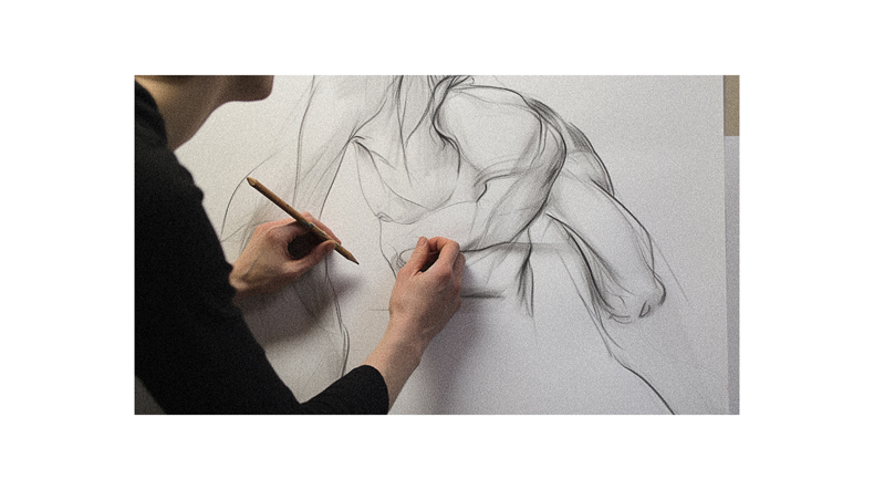A woman is drawing a figure on a piece of paper.