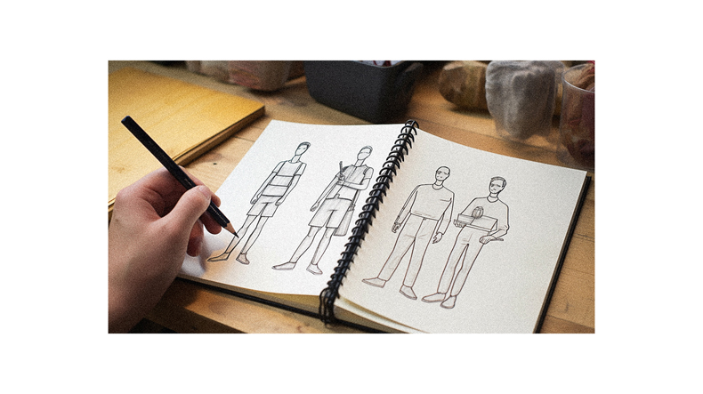 A person is drawing a figure in a notebook.