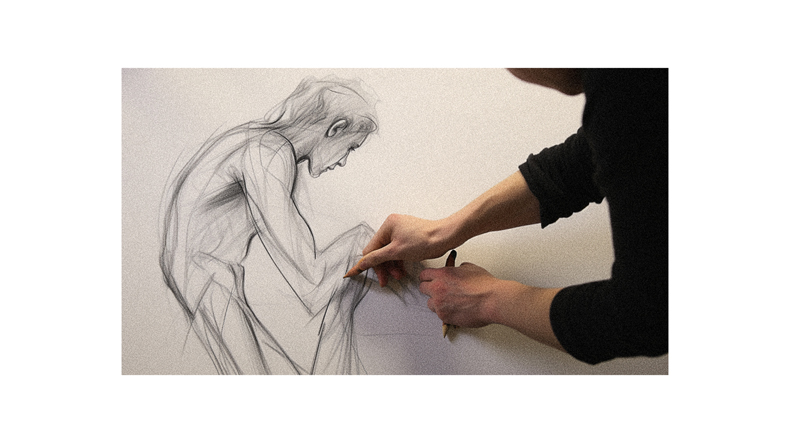 A person drawing a human figure on a white wall.
