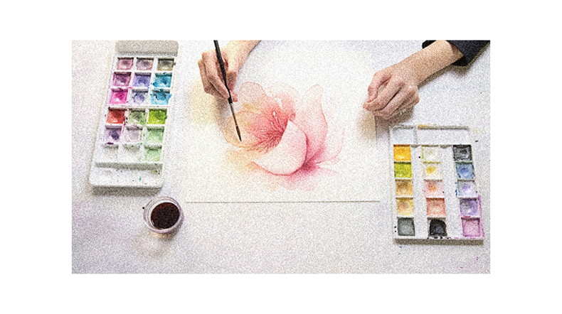 A woman is painting a flower with watercolors.